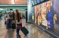 Travelers at Milan Malpensa airport look at a departures board